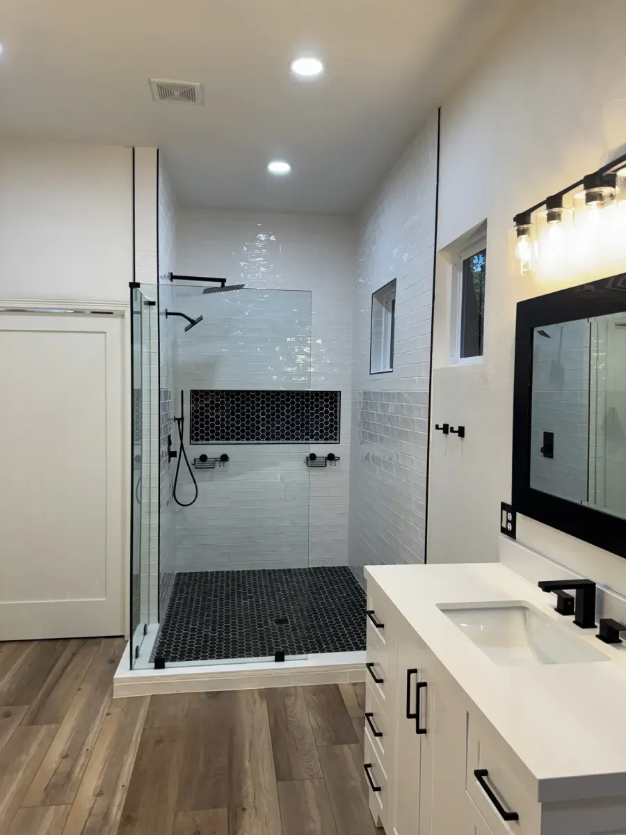 Frameless glass shower with hex tile floor and black fixtures — bathroom remodel in San Antonio, TX
