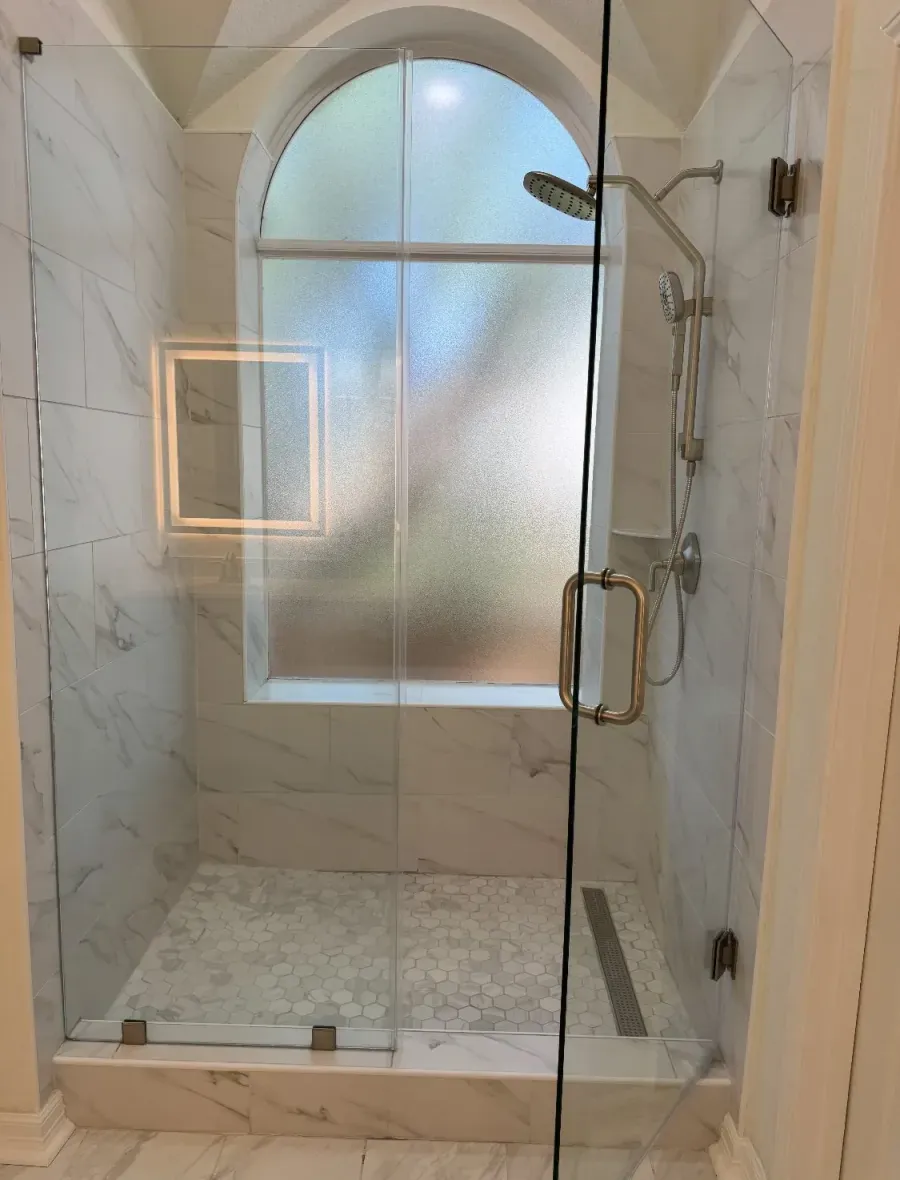 Marble tile walk-in shower with frameless glass and arched window — bathroom remodel in San Antonio, TX