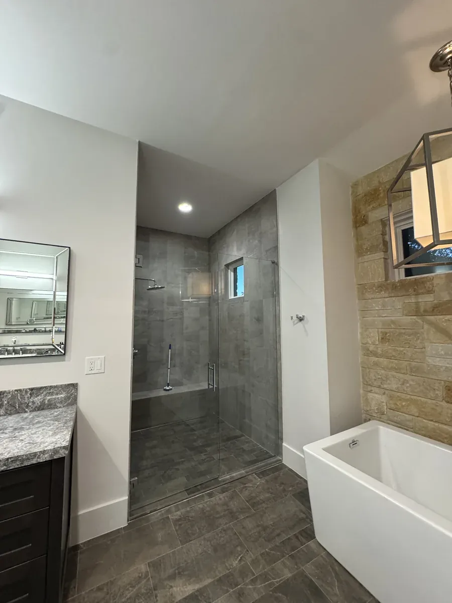 Bathroom remodel with frameless glass walk-in shower, freestanding soaking tub and stacked-stone accent wall in San Antonio, TX